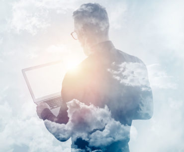 White image with a black shadow of the back of a male figure holding a laptop with clouds around him