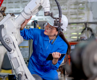 Worker holding tablet and working with robotic machine