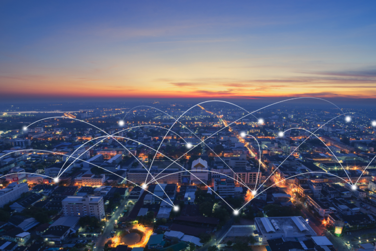 Navigating AI and APIs in Telecommunications: Critical Questions and Insights Communication points connecting one building to another in a city, an aerial view, as the sun is rising in the distance.