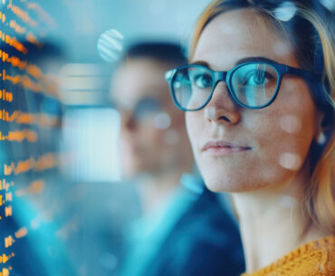 woman wearing glasses, digital screens reflecting off her lenses