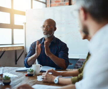 Business leader guiding a team discussion during a strategy meeting in a modern office.