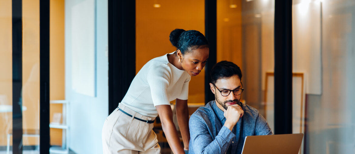 Two marketing professionals reviewing data on a laptop in a modern office, collaborating on omnichannel strategy and performance.