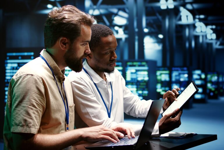 IT professionals collaborating on AI-driven operations using laptops and tablets in a modern data center.