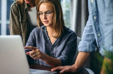 Business professionals collaborating on data analysis and privacy strategy using a laptop in a modern workspace.
